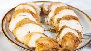 Wide image of instant pot cooked chicken breasts, sliced and on a plate.