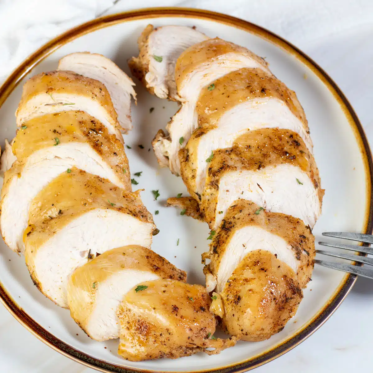 Square image of instant pot cooked chicken breasts, sliced and on a plate.