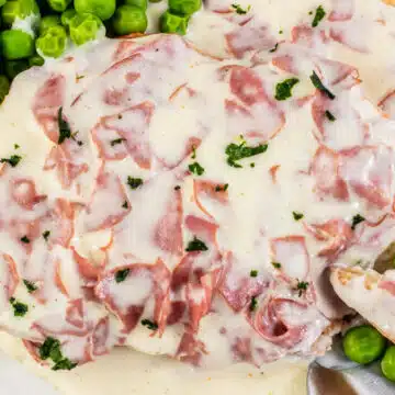 Creamed chipped beef on toast with peas on the side served on tan plate.