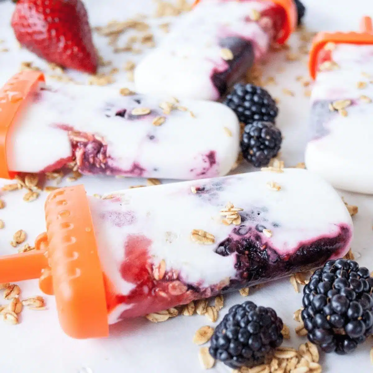 Firkantet billede af græsk yoghurtbær granola ispinde.