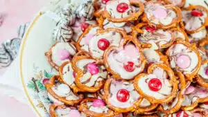 Wide closeup on a plate of no-bake Valentine's Day pretzel hug candies on floral plate.