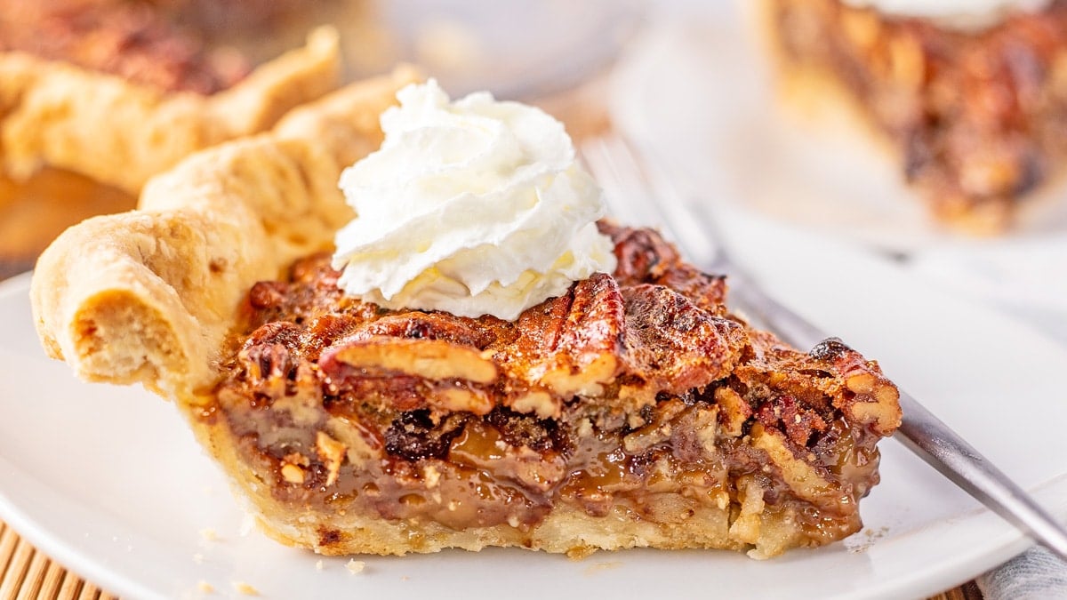 Wide closeup image of sliced Cracker Barrel chocolate pecan pie copycat recipe baked and served on white plate.