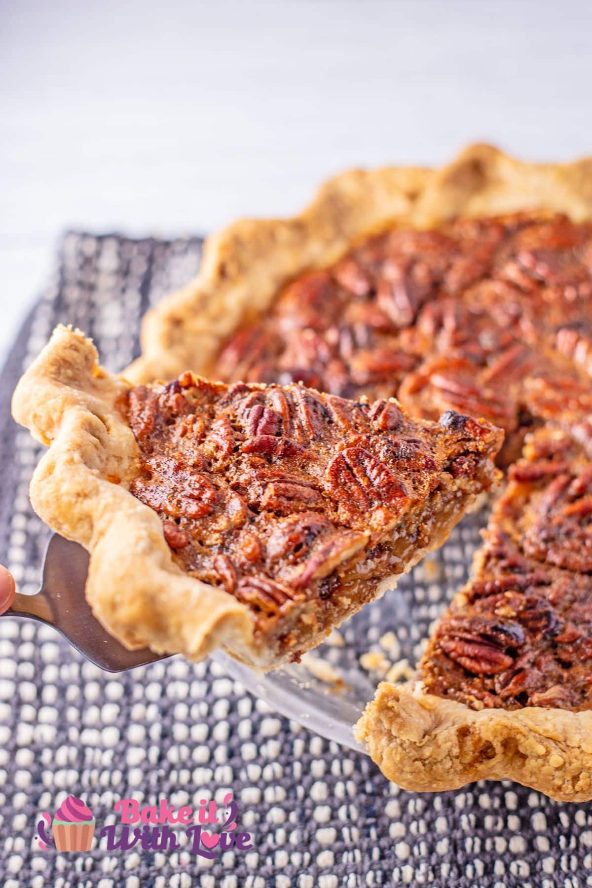 Freshly baked Cracker Barrel chocolate pecan pie copycat baked and sliced, being lifted from the pie pan to serve.