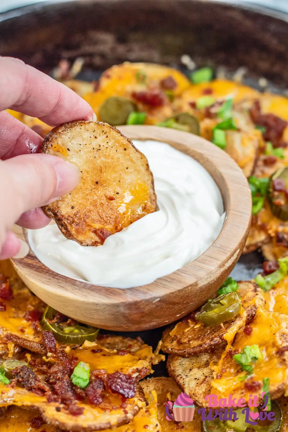 Tall image of Irish nacho being dipped in sour cream.