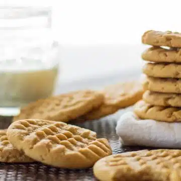 Wide image of peanut butter cookies with a glass of milk.