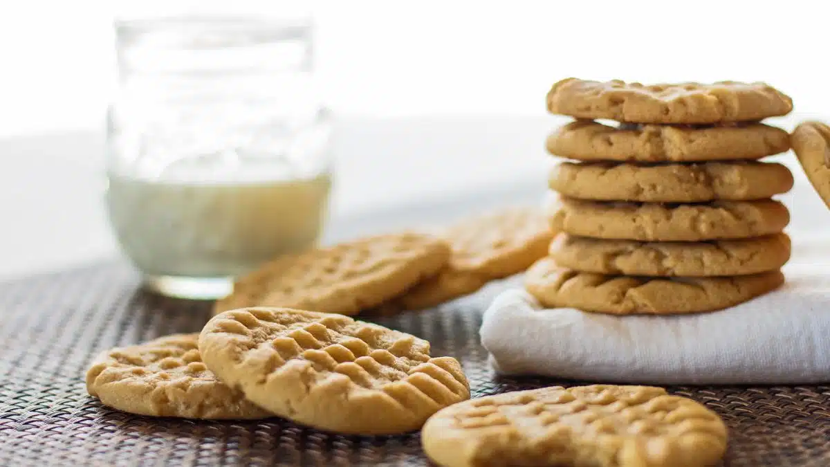 Wide image of peanut butter cookies with a glass of milk.