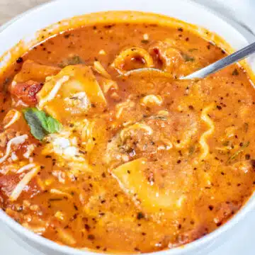 Delicious crockpot lasagna soup with spinach with spoon offset on the side of the bowl after mixing the cheese topping into the soup.