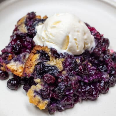 Square image of Bisquick blueberry cobbler with ice cream.