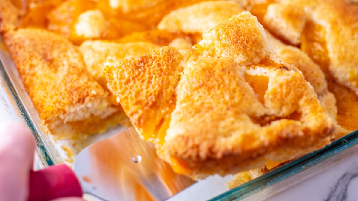 Paula Deen's Southern peach cobbler recipe baked, sliced, and being served up.