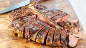 Wide image of a grilled Porterhouse steak on a cutting board.