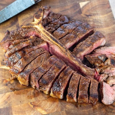 Square image of a grilled Porterhouse steak on a cutting board.