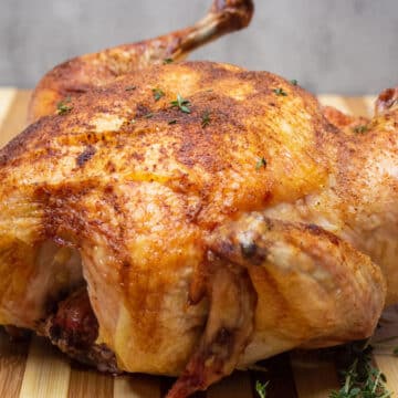 Wide image of roast Capon chicken on a cutting board.