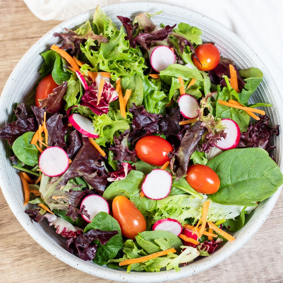 Square overhead image of a green garden salad.