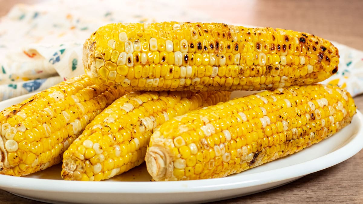 Wide image of grilled corn on the cob.
