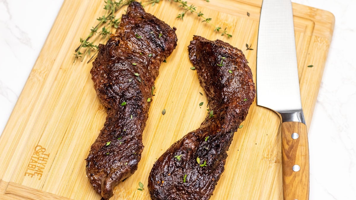 Wide image of hanger steak on a cutting board.