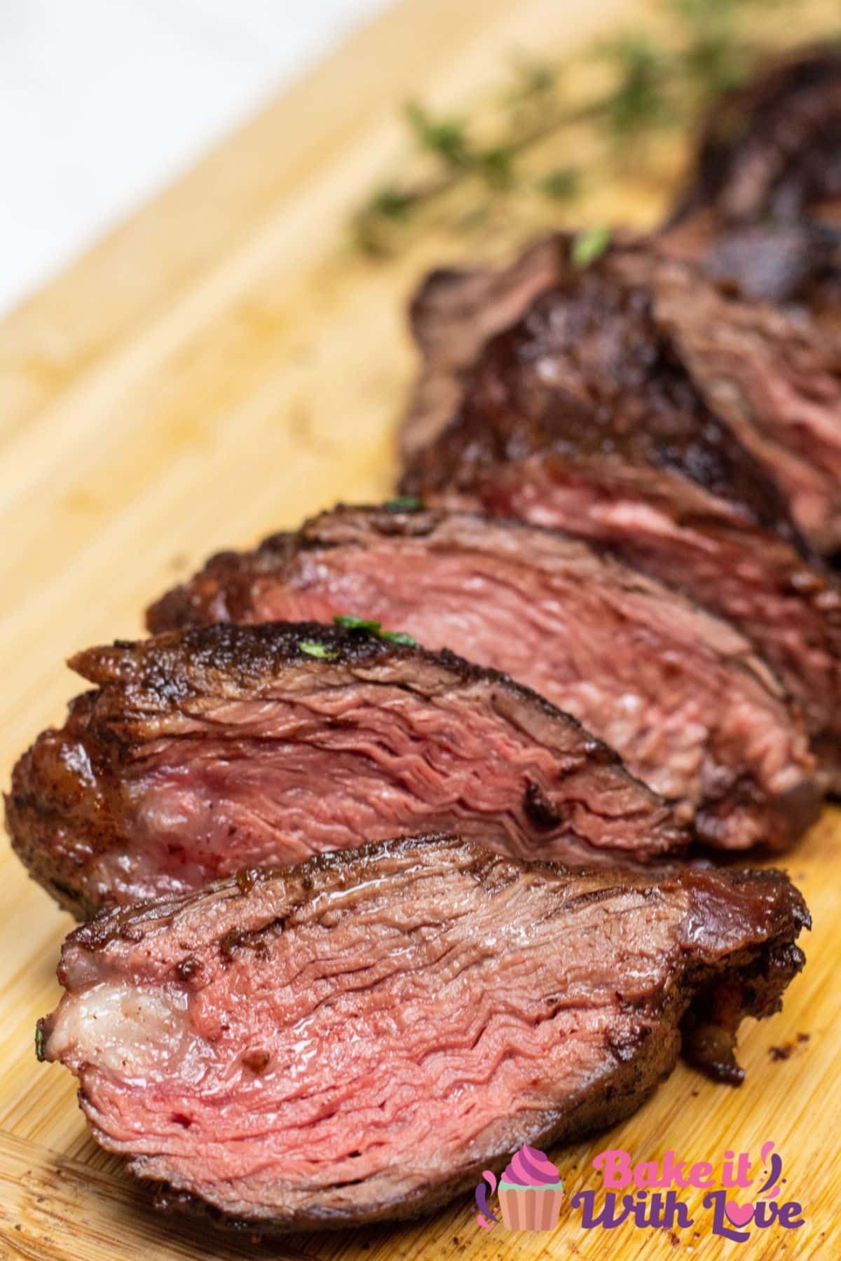 Tall image of hanger steak on a cutting board, sliced.