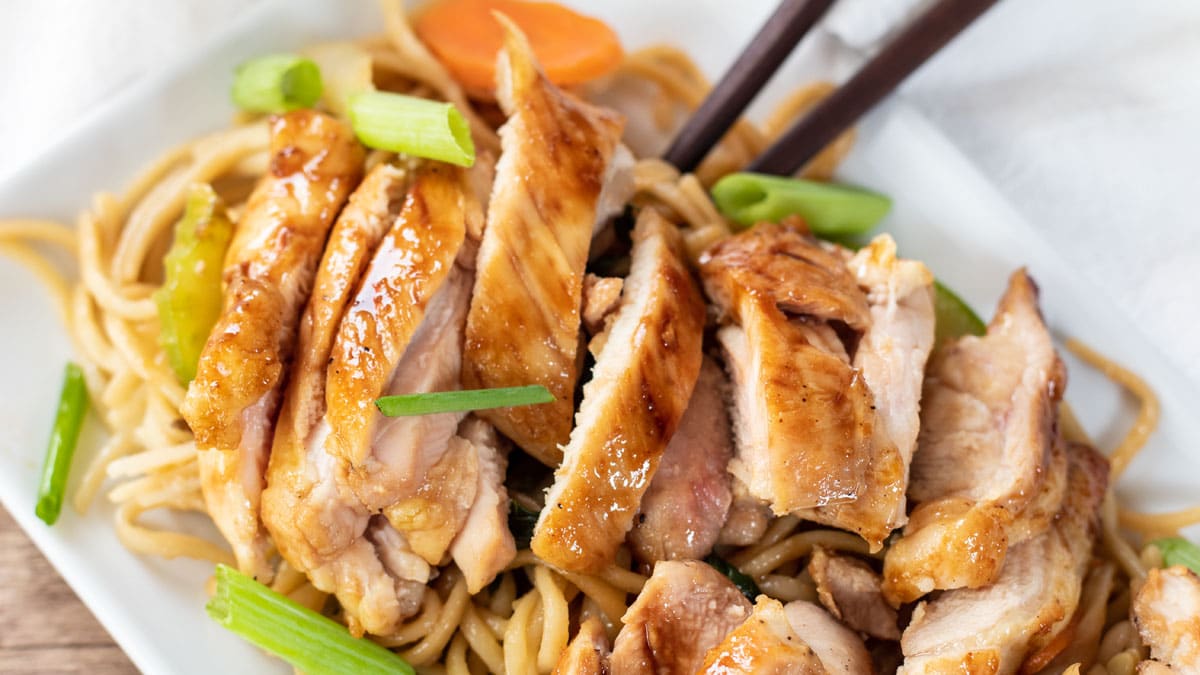 Wide close up image of Panda express teriyaki chicken on a white plate with lo mein.