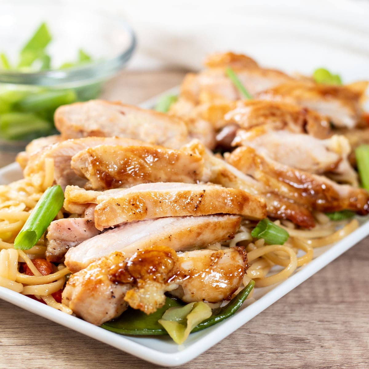 Square image of Panda express teriyaki chicken on a white plate with lo mein.