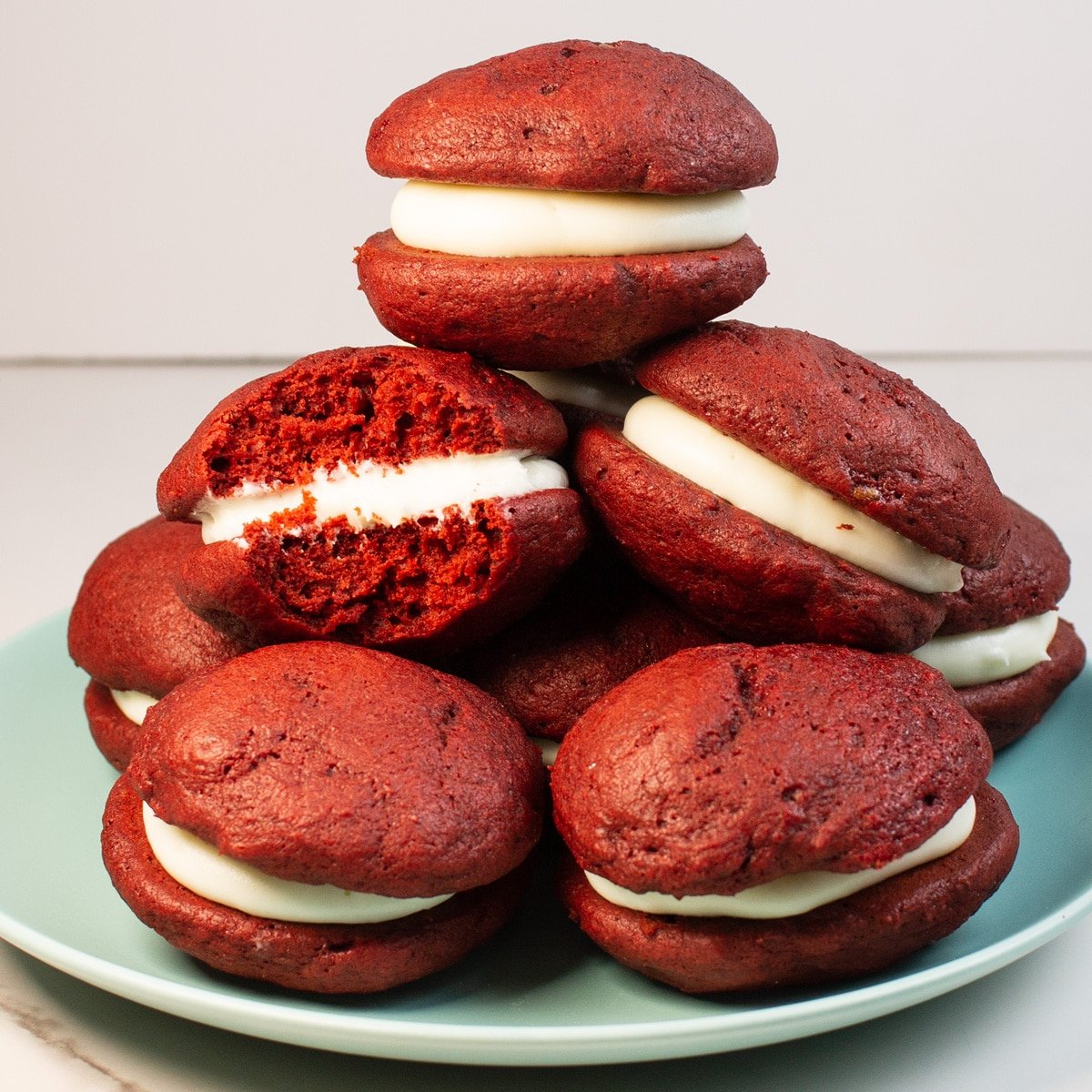 Delicious red velvet whoopie pies stacked on a plate with light background.