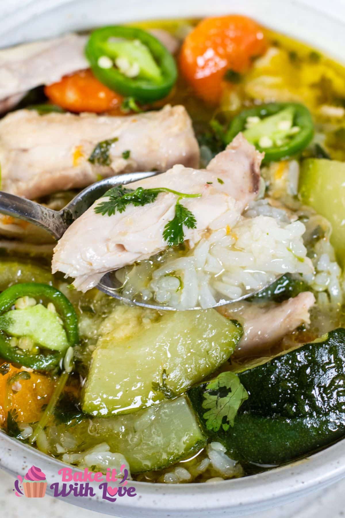 Tall image of caldo de pollo Mexicano soup and spoon holding soup.