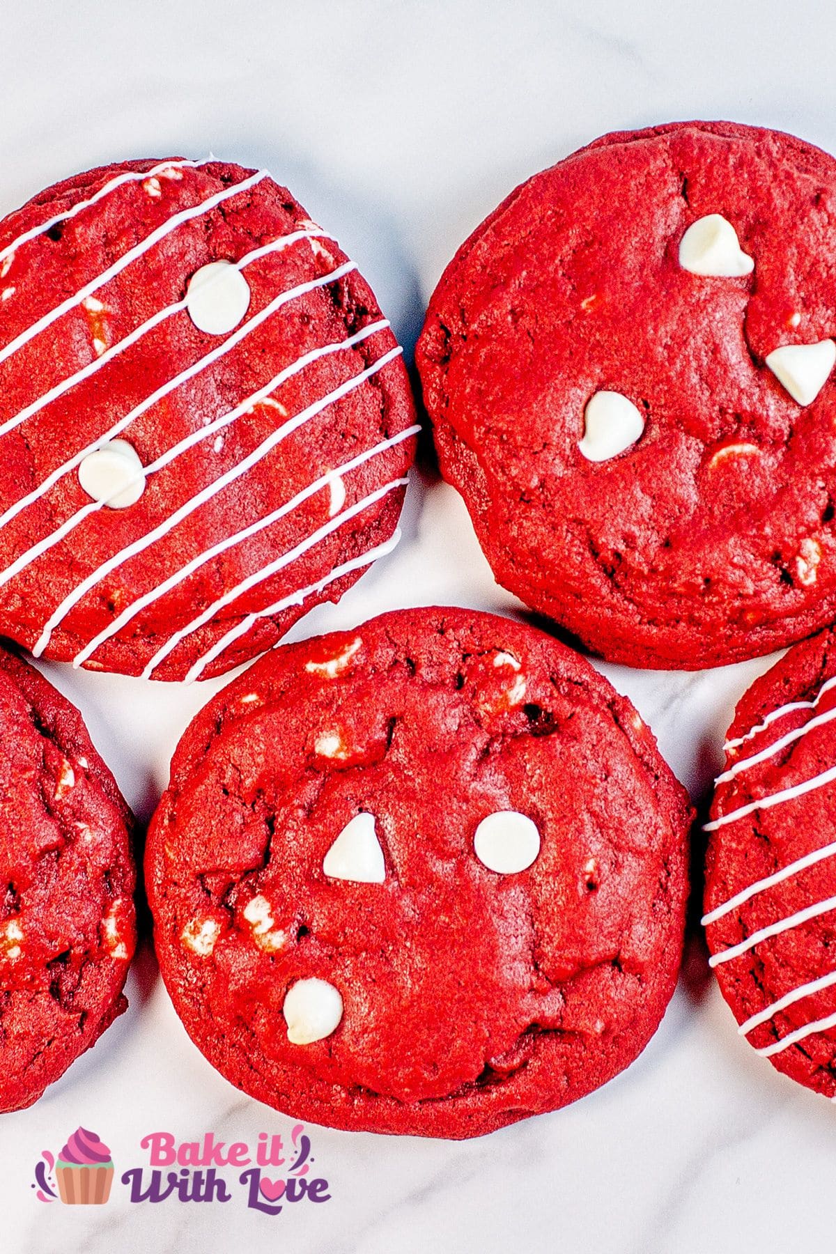 Vertical close up over the baked CRUMBL red velvet white chocolate chip cookies with a few having white chocolate drizzles on them.