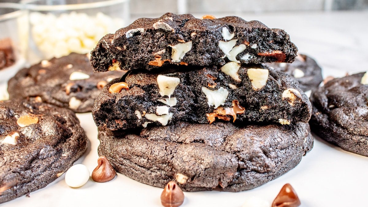 Closeup on Levain Bakery black and white chocolate chip cookies stacked with the top cookie broken in half to show the rich cookie texture.