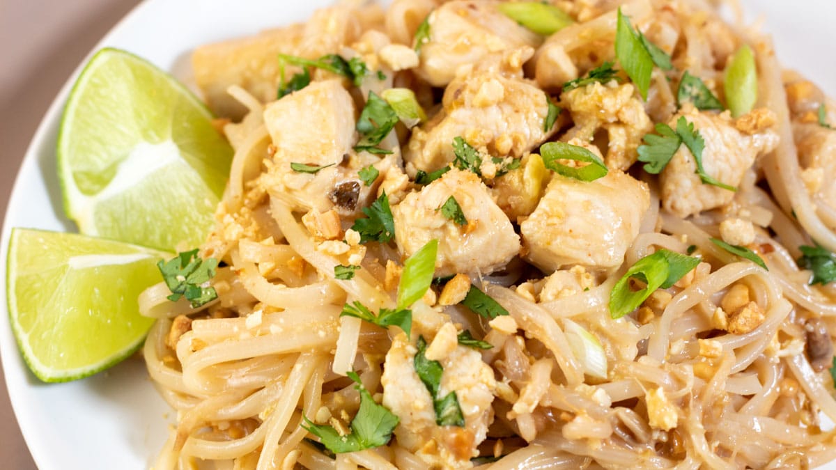 Wide image of pad thai on a white plate.