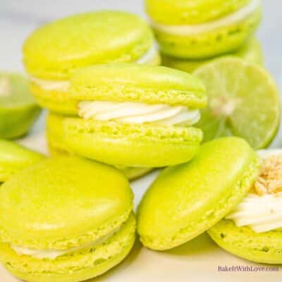 Tangy but sweet key lime macarons stacked on light background with an open one to the bottom right.