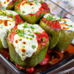 Classic stuffed green peppers in a clear glass 9x13 baking dish topped with fresh chopped parsley.