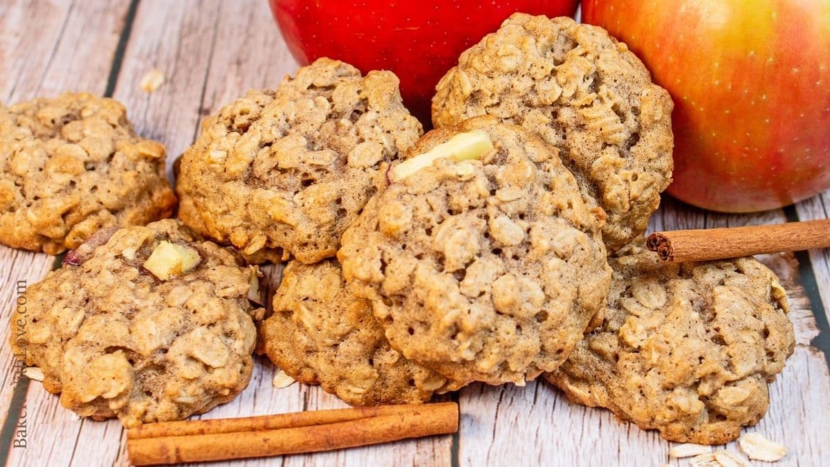 Assorted apple oatmeal cookies on wooden background with apples and cinnamon sticks.