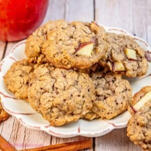 Tasty apple oatmeal cookies arranged on a plate with apple and cinnamon sticks.