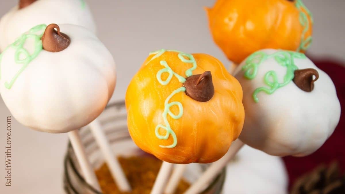 Wide image of pumpkin cake pops in white and orange colors.