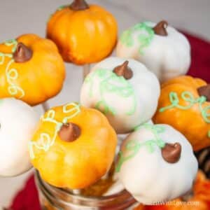 Square image of orange and white pumpkin cake pops in a jar.