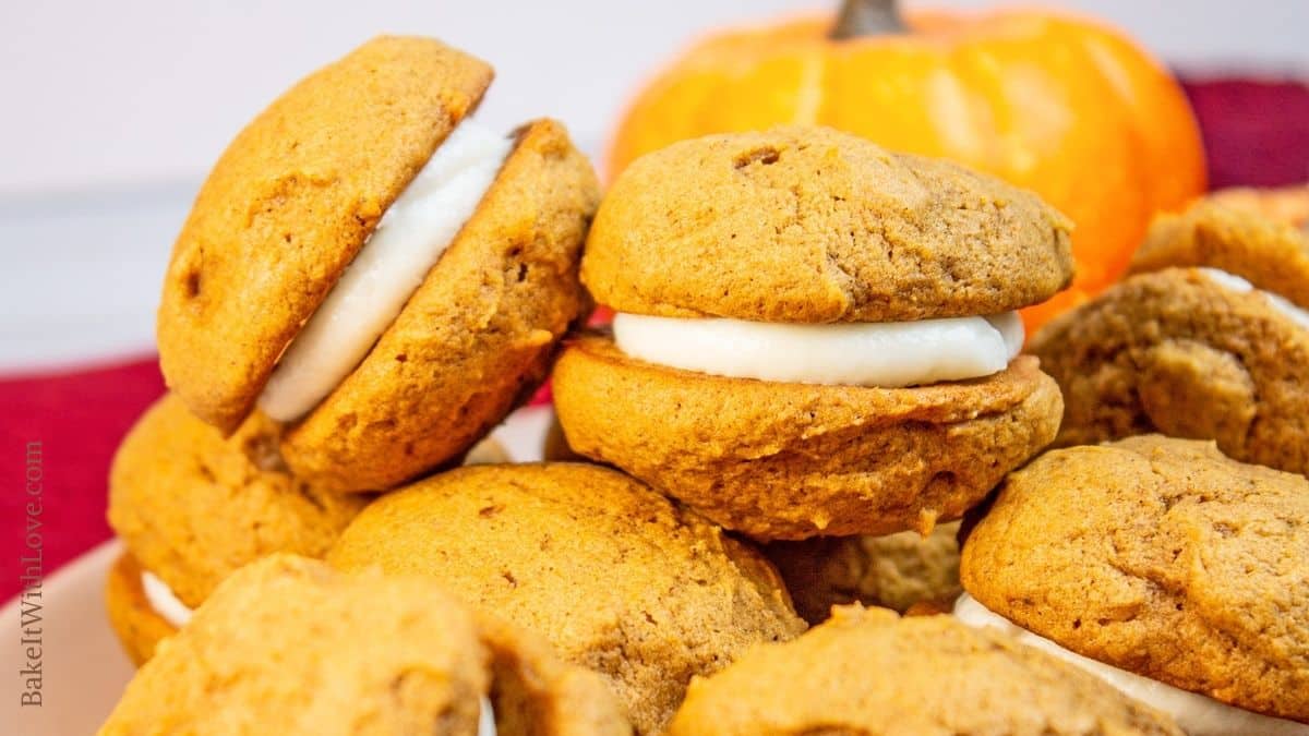 Wide closeup image of the assembled and stacked pumpkin whoopie pies on a plate.