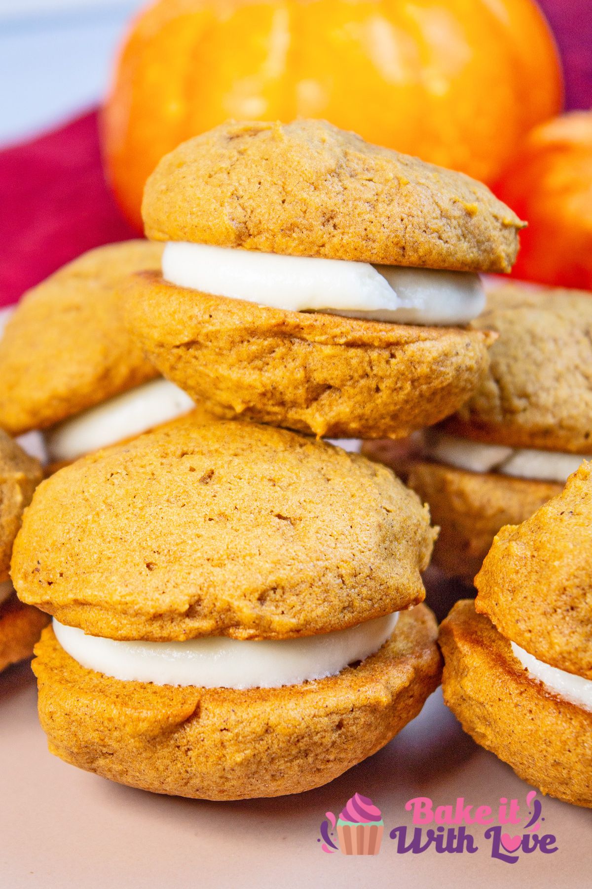 Tall closeup image of two of the stacked pumpkin whoopie pies with cream cheese filling.