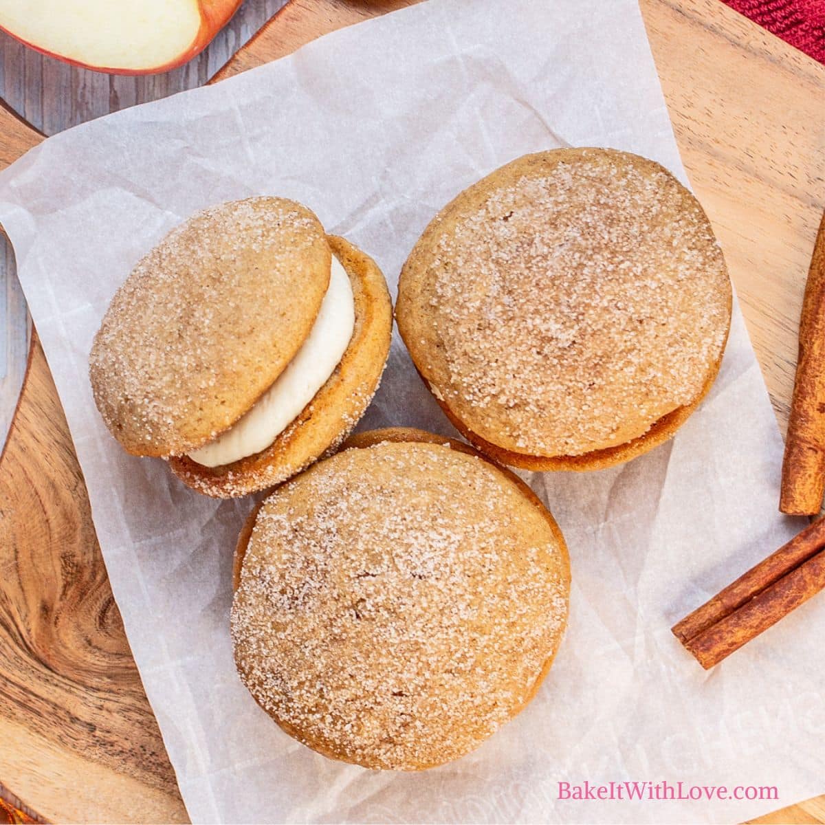 Square image of apple cider whoopie pies on parchment paper.