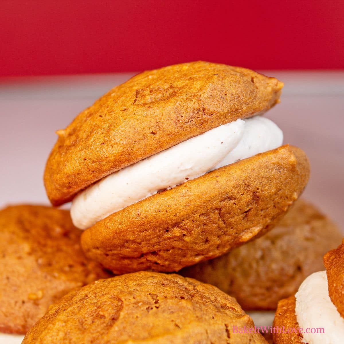 Square image showing a side view of gingerbread whoopie pies with a red background.