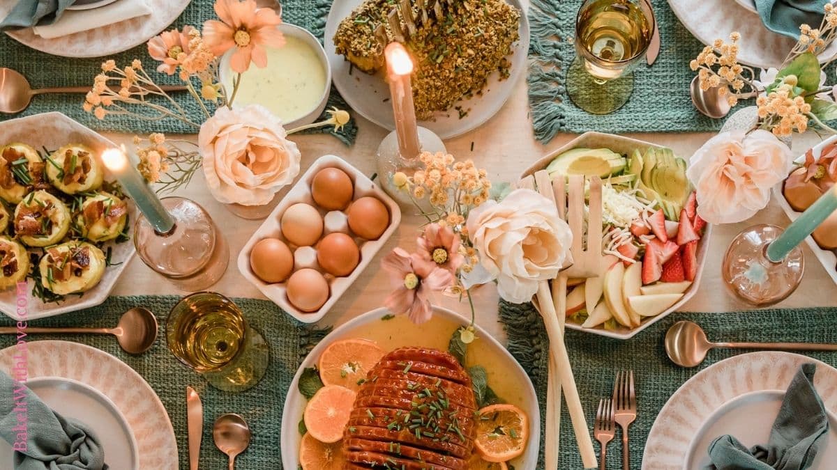 Wide image showing an overhead view of a table with placemats, candles, flowers, and various platters of food.