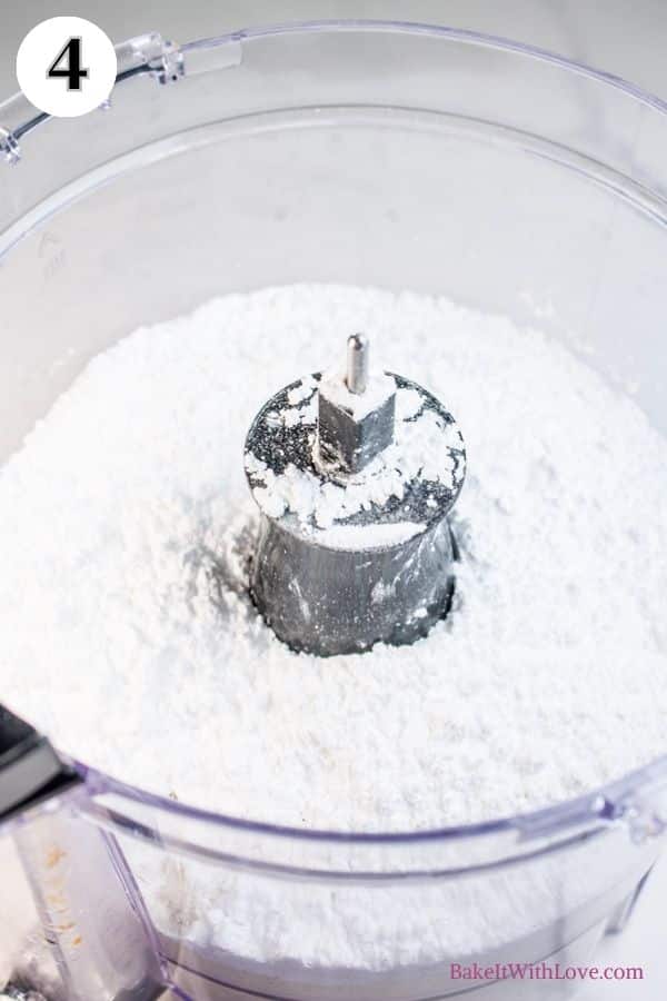 Toasted coconut macarons process photo 4 showing powdered sugar and almond flour in the bowl of a food processor.