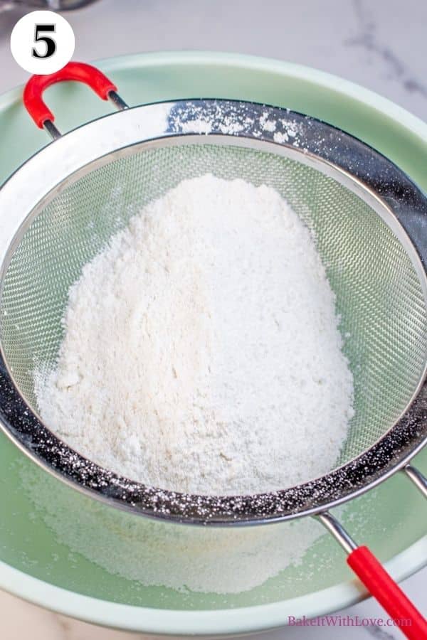 Toasted coconut macarons process photo 5 showing powdered sugar and almond flour being sifted through a sieve into a mixing bowl.