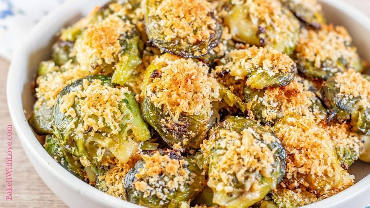 Wide image showing and up-close shot of a bowl full of parmesan smashed brussel sprouts. 