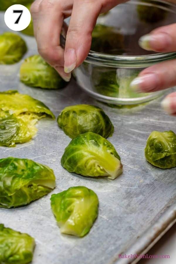 Crispy parmesan smashed brussel sprouts process photo 7 showing a hand using a small glass bowl to smash the brussel sprouts.