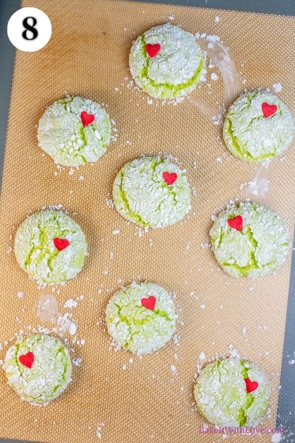 Grinch cookies process photo 8 showing baked Grinch cookies topped with a heart sprinkle on a silicone baking mat. 