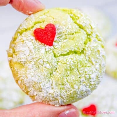 Square image showing a hand holding one of the grinch cookies with a heart sprinkle.