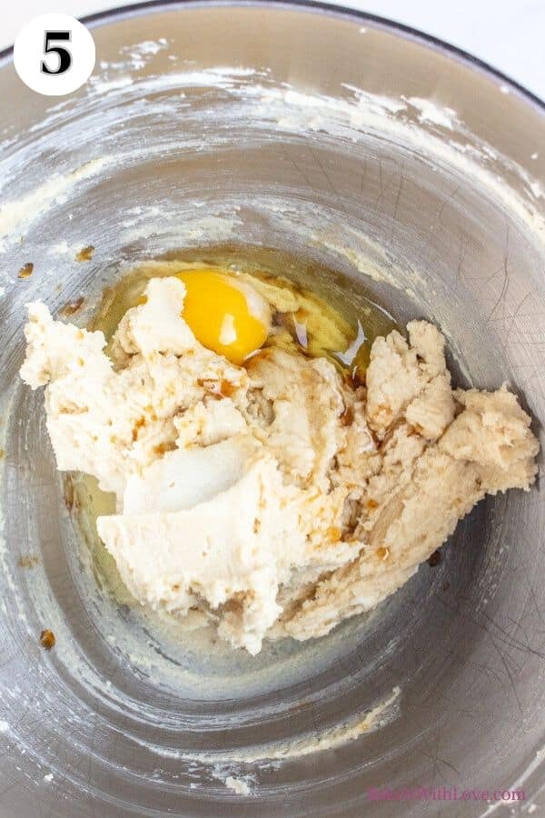 Hot chocolate cookies process photo 5 showing egg and vanilla added to dough in a metal mixing bowl. 