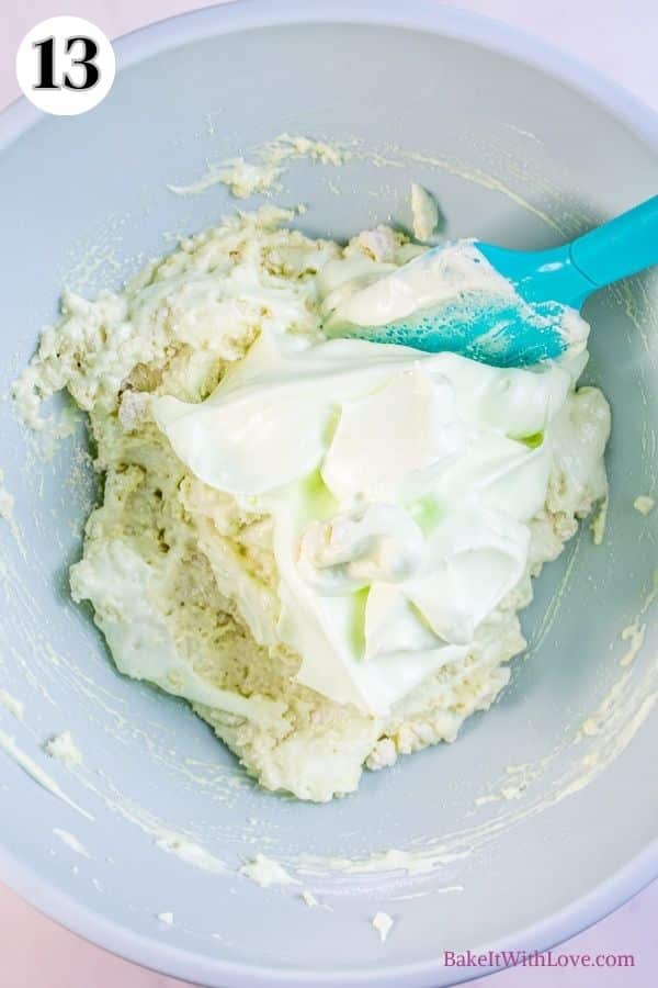 Mint chocolate macarons process photo 13 showing more meringue being added to a mixing bowl of the almond flour and meringue combination. 