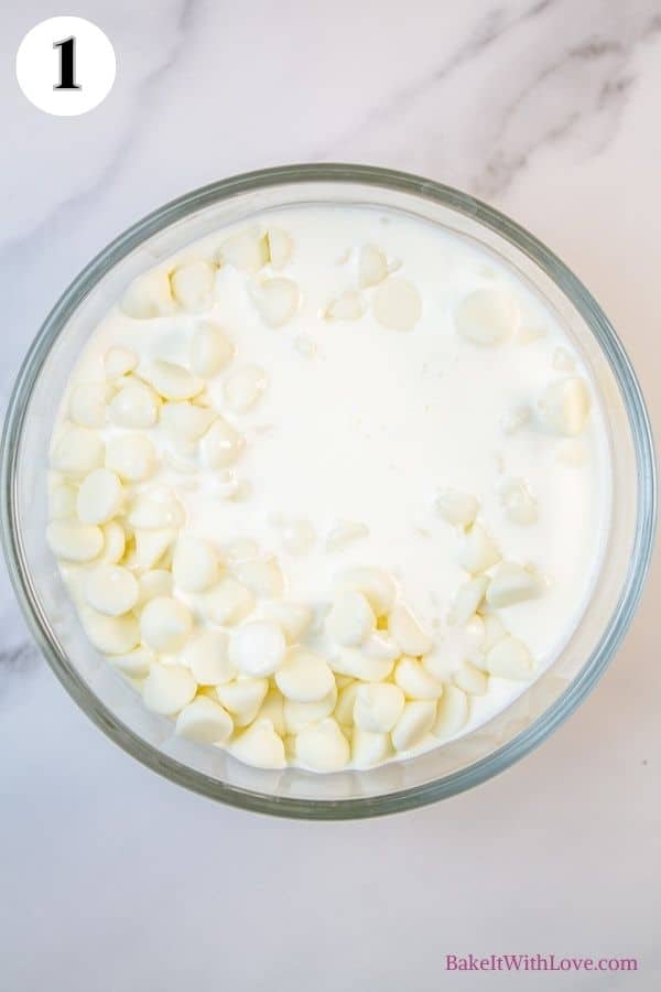 Peppermint macarons process photo 1 showing heavy cream and white chocolate chips in a glass mixing bowl. 