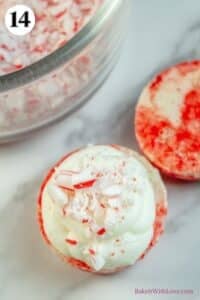 Peppermint macarons process photo 14 showing a macaron shell topped with ganache and crushed candy canes with a bowl of candy canes in the background.