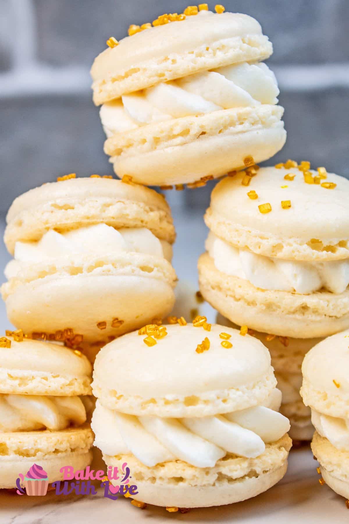 A tower of stacked macarons with gold sprinkles on the macaron shells.