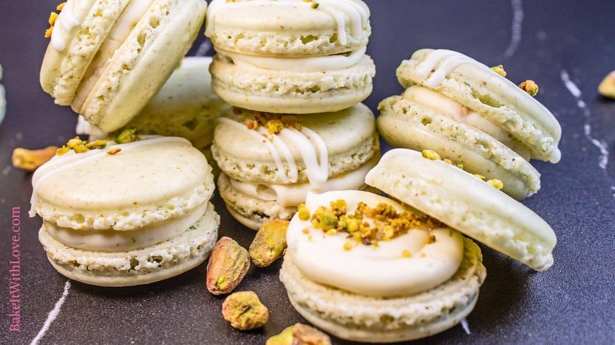 Wide closeup on the stacked pistachio macarons with one at the front showing the filling.